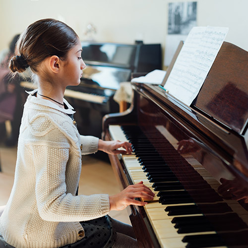 Young piano student practicing at the keyboard